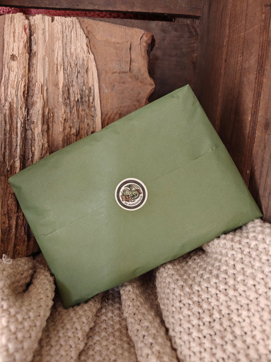 A green paper wrapped package displayed on fabric in a wood case.
